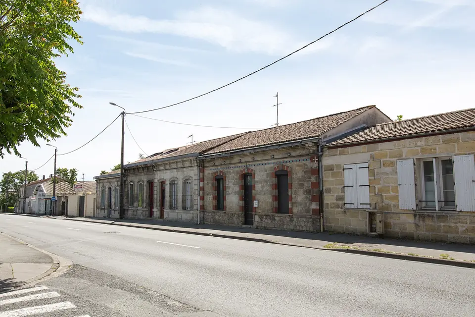 Rangée d'échoppes à Mérignac, maisons basses en pierre calcaire alignées le long d'une rue, avec volets et toitures en tuiles.